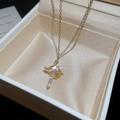Macro del ciondolo a croce dorata con zirconi cubici su una collana a catena sottile - Croce / Oro rosa