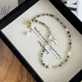 Detail of colorful beads and baroque pearls with gold lobster clasp on jewelry tray - Necklace / Green Tea Necklace