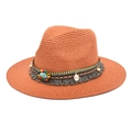 Detail of a brick red straw fedora featuring ethnic beads and a turquoise tassel band - Caramel color