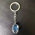 Silver keychain featuring an oval resin pendant with blue dried lace flowers - Oval Blue Lace Flower