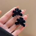 Pair of small black flocked bow hair clips held by hand for elegant hairstyling - Flocked Bow Small Hair Claw / Black