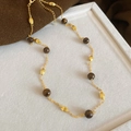 Detail van vintage gouden ketting met tijgeroog kralen op een luxe sieradendisplay - Afwisselende Ronde en Olijf Kralen Stijl (Nr. 6 Ketting - Goud - Bruin)