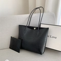 Bolso tote negro con textura de cocodrilo y estuche con cremallera sobre fondo gris suave - Negro
