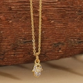 Detailopname van gouden Hamsa-hand met paarse stenen op een natuurlijke houten achtergrond - Witte Zirconia Hamsa Hand