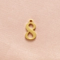 Close-up of golden number 8 pendant in stainless steel on pink fabric background - Gold Number 8