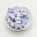 Macro shot of purple gradient bear-shaped beads in a white decorative plate for DIY crafts - Purple