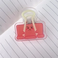 Nahaufnahme des rosa Acryl-Binder-Clips mit lustigem Gesicht auf Linienpapier - Rosa
