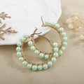 Detail of gold circle earrings featuring hand-wrapped mint green pearls on a ceramic plate - Mint Green