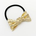 Detailweergave van een gouden metalen strik haarclip met een elegante geplooide textuur - Goud