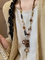 Detailed close-up of a vintage pearl flower necklace with Believe pendant on a model - Believe Style - Dark Brown