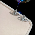 Macro shot of silver planet earrings with sparkling zircons on pink velvet box - Planet Star Stud Earrings / Silver