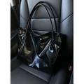 Black glossy oil wax leather tote bag with heart pendant on car leather seat - Black