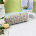 Close-up of quilted cotton floral bag with blue zipper and puffy texture detail - Green Plaid Floral