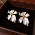 Detailed top view of silver flower earrings with gold stamens on black velvet lining - Silver