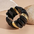 Close-up of geometric black and gold acrylic bangle with sleek metallic texture detail - Black