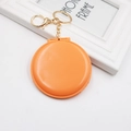 Detail of an orange round folding mirror keychain with a gold chain and metal ring clip - Orange