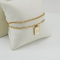 Pulsera dorada de doble capa con un colgante rectangular con la inicial E grabada - Letra E