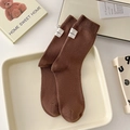 Dunkelbraune gerippte Baumwollsocken mit weißem Webetikett in gemütlicher Kulisse - Einheitsgröße / Kaffeebraun