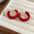 Detailed view of red velvet circular earrings with gold metal base and spiral texture - Red