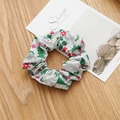 Détail d'un chouchou en tissu gris avec motif sapin de Noël sur une surface boisée festive - Sapin de Noël Gris