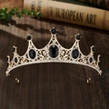 Close-up of golden crown with black oval gemstones and rhinestones on wood - Gold Black Zirconia