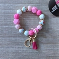 Macro detail of pink silicone beads, suede tassel, and golden hardware on key ring - Rose Red