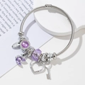 Silver charm bracelet with purple crystals, swan and heart charms on a clean background - Purple