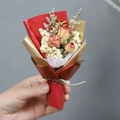 Nahaufnahme eines Mini-Trockenblumenstraußes mit roten Rosen und Schleierkraut - Rote Rose (Rote Verpackung)