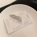 Fermaglio in metallo argento con ciondolo a fiocco su un piatto bianco minimale - 1 Fiocco (Singolo)