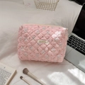 Close-up of quilted pink makeup bag with floral bunny print and metal brand label - Skateboard Rabbit