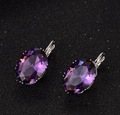 Dettaglio macro di orecchini di zircone viola ovale con montatura in argento lucido - Fucsia