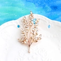 Elegant gold leaf brooch with champagne crystals on white ceramic plate background - Gold and Champagne