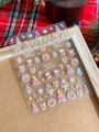 Macro detail of laser Christmas nail stickers with snowflakes and trees on festive background - YT4198 Pink Purple Laser Embossed