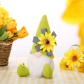 Detailed plush gnome with sunflower hat, white beard, and small bee on gingham tablecloth - Green Hat Style