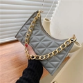 Detail of grey quilted shoulder bag featuring a chunky gold chain strap and zipper - Gray
