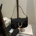 Glossy black patent leather shoulder bag with bold gold horseshoe buckle and strap - Black