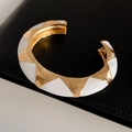 Dettaglio del bracciale aperto dorato con smalto bianco e motivi geometrici su pelle - Stile Aperto Largo / Oro & Bianco