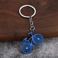 Blue alloy bicycle keychain with gemstone wheel detail on rustic stone background - Blue