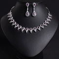 Elegant silver bridal jewelry set with purple teardrop gems and crystals on a black stand - Purple Zircon Necklace & Earring Set