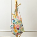 Detail of floral canvas tote bag with colorful rose patterns hanging on a wooden rack - Spring Garden Floral