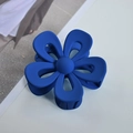 Macro detail of a large matte blue flower hair claw clip on a clean white desk surface - Dark Blue