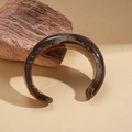 Detailed close-up of amber resin cuff bracelet with marble texture on rock - Gray