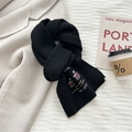 Detail of black knit wool scarf featuring embroidered inspirational quotes and text patch - Black