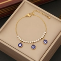 Bracciale dorato con ciondoli occhio blu e zirconi bianchi su una scatola da regalo - Stile Malocchio Tondo Blu (2#)