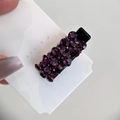 Détail d'une pince à cheveux en strass violets tenue sur une carte blanche - Fuchsia