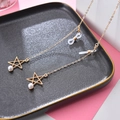 Goldene Brillenkette mit Sternanhänger und weißer Perle auf strukturiertem Tablett - Perle Stern Gold