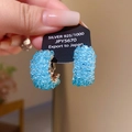 Détail de l'étiquette Argent 925 sur une boucle d'oreille en perles bleues et cristal - Tige en Argent 925 - Anneau Perlé Bleu Argenté