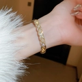 Dettaglio del bracciale dorato trapuntato con zirconi incastonati indossato sopra un polsino - Bracciale Rigido con Zirconi Trapuntato / Oro