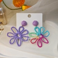 Macro detail of purple and colorful woven raffia flower earrings on white card - Asymmetric Color