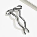 Detailopname van een zilver-zwarte metalen haarspeld met een stijlvol strikontwerp - Zwart